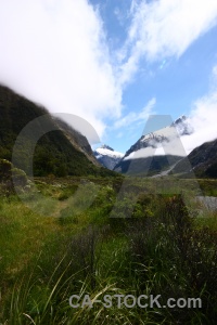 Mountain landscape grass snowcap sky.